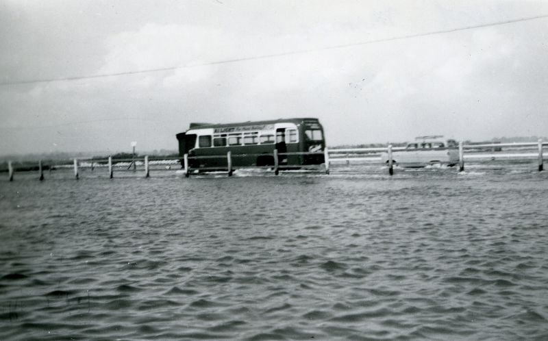  Eastern National bus going through the water at the Strood, in the days when bus services were not curtailed by the high tide. Ford Anglia Estate behind it ? 
Cat1 Mersea-->Strood Cat2 Transport - buses and carriers