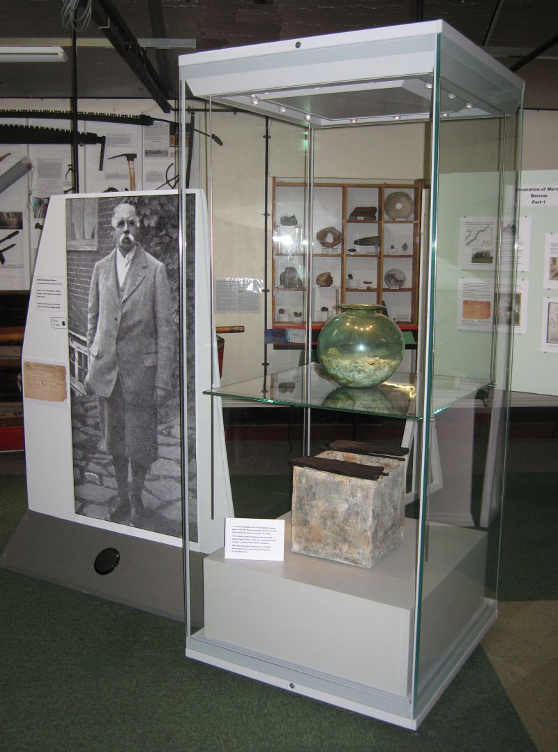  2012 Summer Exhibition. Samuel Hazzledine Warren. Display cabinet with contents of the tomb from Mersea Barrow - the glass urn containing cremated bones, and underneath it, the lead box. 
Cat1 Museum-->Exhibition Views Cat2 Museum-->History Cat3 Mersea-->Barrow-->Pictures