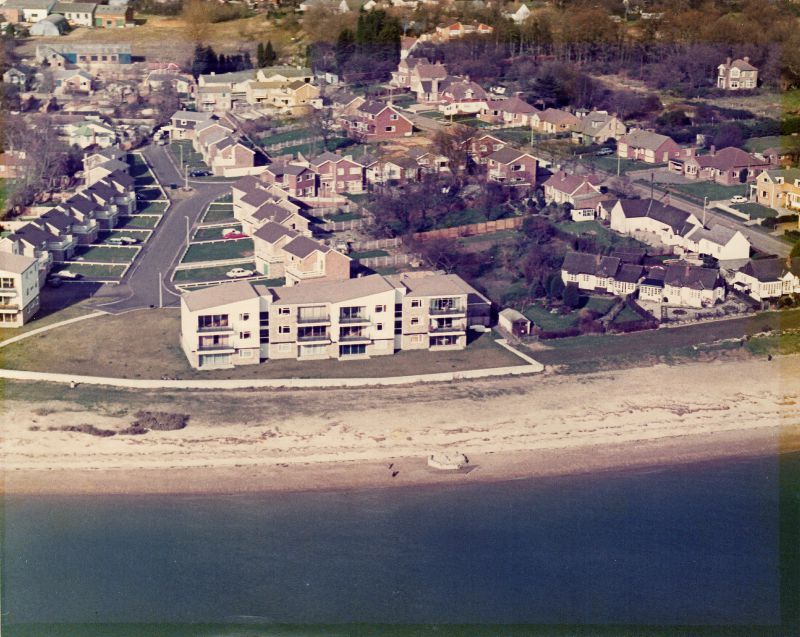  Shears Court and Shears Crescent in the early 1970s. Photograph from Ronnie Fisher, who lived in the top right flat in Shears Court.

The base of the pillbox is clearly visible on the beach.

The house on the corner of Broomhills Road and Shears Crescent just has the footings complete, dating the photograph to 1969 or 1970. Courtneys, standing in isolation top right, is now on 'The ...
Cat1 Mersea-->Buildings Cat2 Mersea-->Beach Cat3 Aerial Views-->Mersea