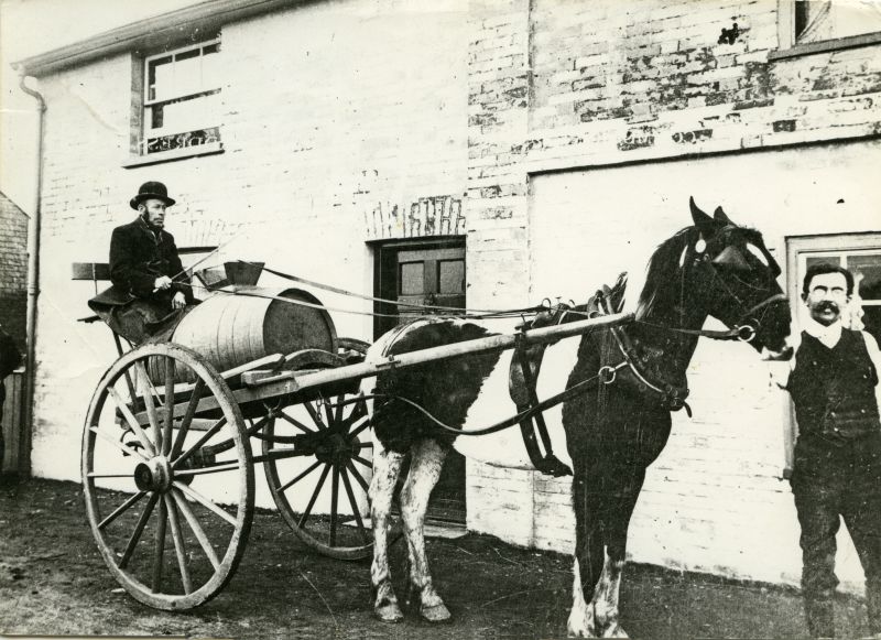  Abberton Water Cart. Eddie Smith holding the horse. The cart was used to supply water to the village from the well under the bakery. Eddie Smith donated land at the back of the site so a water tower could be built to provide a public water supply for Abberton. 
Cat1 Places-->Abberton Cat2 Transport - buses and carriers