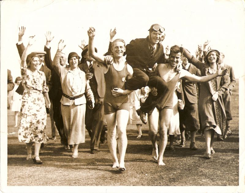  Mr Charles Scott lands on the Golf Course near the sea and is carried by two bathers, followed by local folk. Mrs Scott is on the right (wearing a coat). The bather on the left of the picture is Frank French. 
Cat1 Mersea-->Golf Club Cat2 Mersea-->Events
