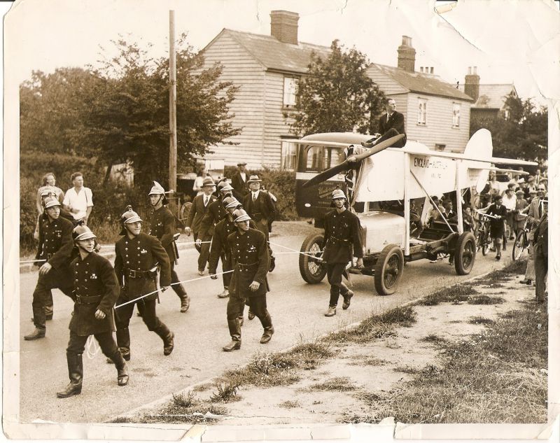  Mr Charles Scott's journey through the village, towed by firemen. C.W.A. Scott was an aviator who had flown to Australia. He was a Mersea resident. Picture was taken on Colchester Road, Mersea. There is an Underwood's bus in the background. 
Cat1 Mersea-->Events