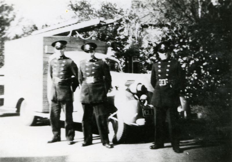  West Mersea Fire Brigade. The fire engine is an American car (Hudson Terraplane Bell) converted with a wooden back, for Fire Service use.

L-R Gordon Mussett, Ernie Dixon (Leading Fireman), Harold Hollohan or Holahan. 
Cat1 Mersea-->Fire Brigade Cat2 Families-->Mussett