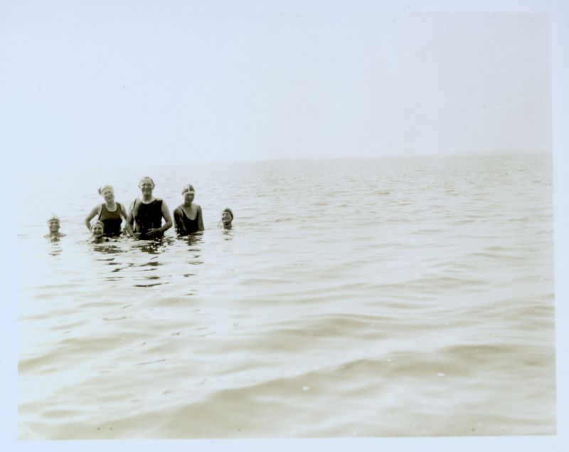  Howard Winch in the centre and to the left of him are his daughter Betty Winch wiht little Patricia (Fairy) Winch in front. At extreme right is Moira Winch. The other two girls unknown. Swimming at the bottom of Beach Road. 
Cat1 Mersea-->Beach