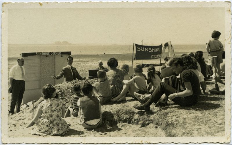  Sunshine Corner on West Mersea Beach. It evolved into the Beach Club. 

Conducting is Alan Barrow from London. On the left is Arthur Briars. Playing the organ (background left of centre) is Howard Weaver.

There are many more images from this Sunshine Corner available in the Museum. 
Cat1 Mersea-->Beach