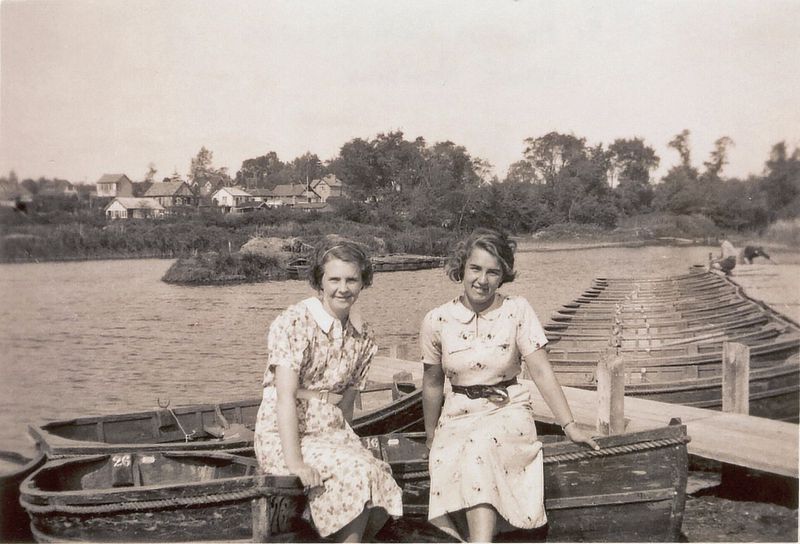  West Mersea Boating Lake, Shears Meadow. Goings Lane and Kingsland Road in the background. The lady on the right is Muriel Smith. The boats are the 'new' boats built for the lake just before WW2.

Muriel Smith ws the daughter of Tom Smith of the Mill family. 
Cat1 Mersea-->Beach