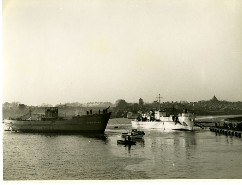  A quiet interlude during war. Wooden motor minesweeper FY PT 1044 is towed to the fitting out berth after launch from Wivenhoe Shipyard Ltd., in 1943. The river Colne brims at mid-day high water and the ship floats high without her engines, equipment, fuel, water and stores. A motor launch tows her in towards hands waiting to moor her at the Railway Quay (right).

The light gray, dazzle ...
Cat1 Places-->Wivenhoe-->Shipyards Cat2 Ships and Boats-->Naval Cat3 Places-->Rowhedge Cat4 War-->World War 2