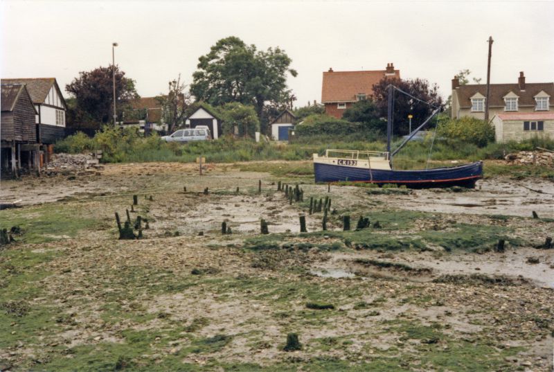  Looking across old oyster pits to Coast Road. CK132. The sheds on the left had become known as the old oyster sheds by the time they were demolished in January 2011, after a long fight to keep them. 
Cat1 Mersea-->Coast Road