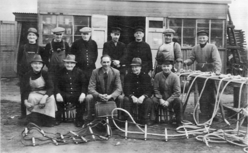 Click to Slide Show


 Ernest Appleton (front row on the left) amongst a group of workers employed by Gowens in Tollesbury during WW2. They made rope ladders, scramble nets etc.

Back row L to R. 1. Jim Appleton, 2. Jimmy Lewis, 3. Will Frost, 4. Dick Holder, 5. Charlie Pettican, 6. Dick Lewis, 7. Silas South.

Front row L to R. 1. Ernie Appleton (twin of Jim), 2. Bob Appleton (brother of Jim and Ernie), 3. Ken ...
Cat1 Tollesbury-->People Cat2 People-->Fishermen and Seamen Cat3 Tollesbury-->Shops and Businesses