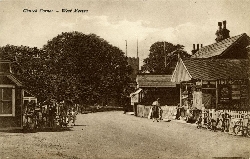  Church Corner, West Mersea. Yorick Road on the left, church in the distance past Eliza D'Wit's Oysters and Refreshments. Postcard 15781.

Owen Fletcher wrote The local lads of the time used to upset Brassy Mussett by throwing stones onto the shop's tin roof. One day, Brassy came out of the shop to give chase, he was tripped by one of the lads, he fell and his false teeth came out, shot ...
Cat1 Mersea-->Road Scenes