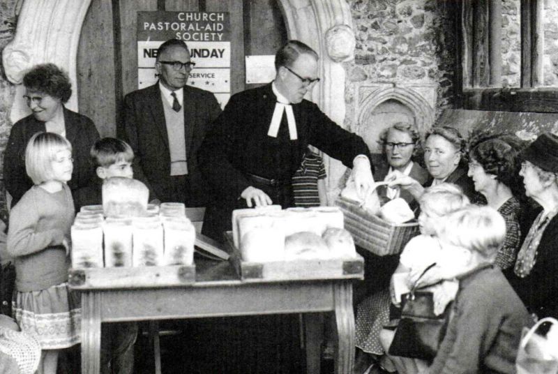  Comyns Charity - distribution of the bread in St Mary's Church Porch, Peldon. 

L-R ?, ?, little boy behind loaf John Walker, Stan May, Rev. Anthony Gough, seated Barbara Wilson, Miss Joyce Thursby, Mrs Judy Thimbleby, Mrs Elsie Miller. The boy front right is Gordon Walker. 
Cat1 Places-->Peldon-->People