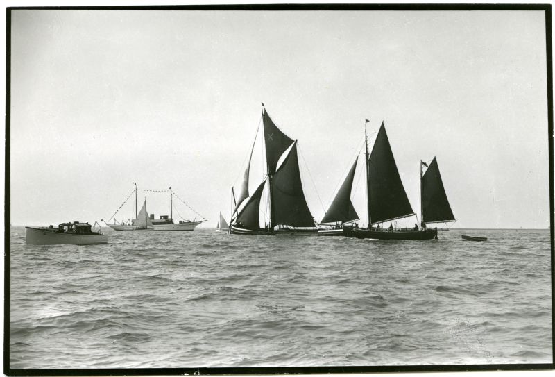  Barge, French fishing boat and other craft leaving Harwich Harbour. [DW]

A mixture of craft at Harwich regatta, 1938. One of R. and W. Paul's Ipswich sailing barges turns to seaward in a light air, amongst the yachts, deep loaded and with her bowsprit still topped up. Her white 'staysail' as bargement term a jib topsail, is set to the stem head. The white cross in her topsail was her owner's ...
Cat1 Barges-->Pictures Cat2 Places-->Harwich Cat3 Yachts and yachting-->Motor