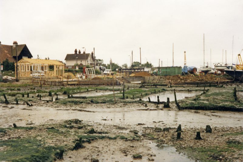  Looking across the old oyster pits to Besom House, Victory Hotel and the Burma Road. Shed under construction. 
Cat1 Mersea-->Coast Road Cat2 Mersea-->Pubs