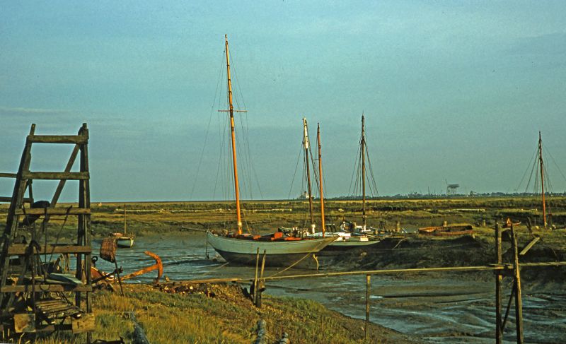  Woodrolfe, Tollesbury. In the distance behind the yawl can be seen a Shaw Savill boat, thought to be the GOTHIC. The large crane for Bradwell Nuclear Power Station is under construction.

From a 1950s slide taken by Mary Sime. 
Cat1 Tollesbury-->Woodrolfe