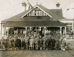  East Mersea Golf Club. Members assembling on the verandah of the clubhouse on the opening day for the full 18 hole course. 
 The photograph was tucked into the Mersea Golf Club Minutes Book. It is from Sporting and General Press Agency.  MMC_P747C_001